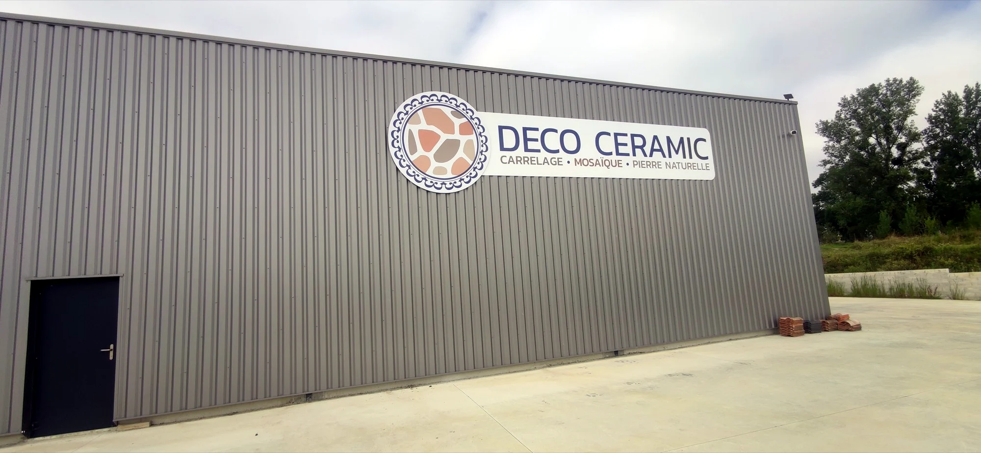 Enseigne Deco Ceramic sur le bardage gris d’un bâtiment professionnel