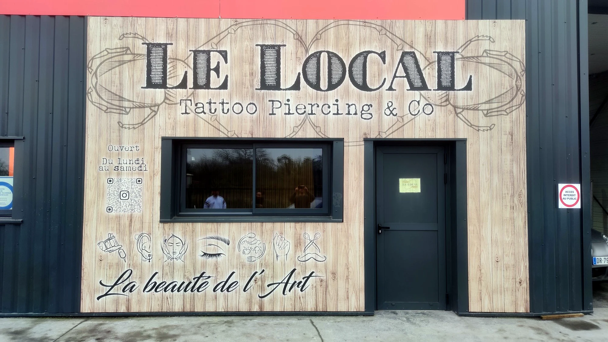 Façade du salon Le Local, Tattoo Piercing & Co, habillée d’un panneau effet bois avec lettrage