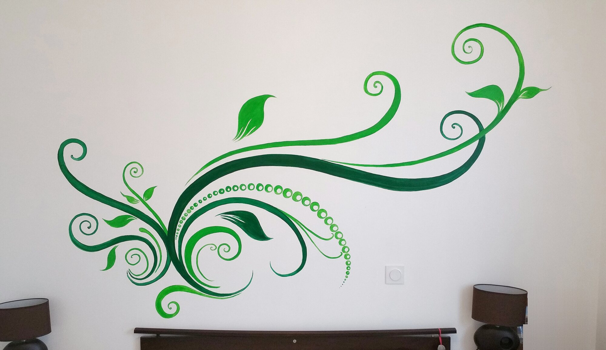 Motif floral vert peint à la main au-dessus d’une tête de lit – chambre à Blaye