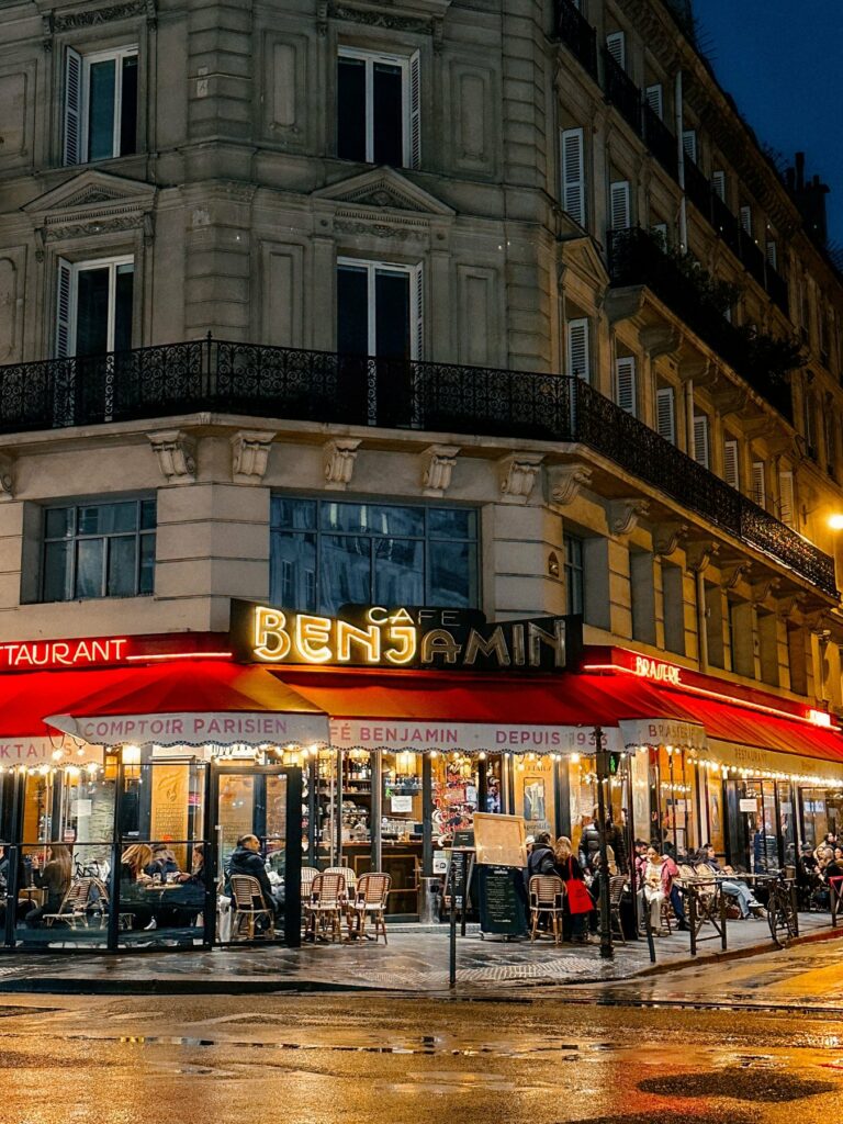 Restaurant d’angle avec stores bannes rouges le soir